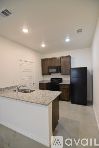 A kitchen with a granite countertop and a black refrigerator.
