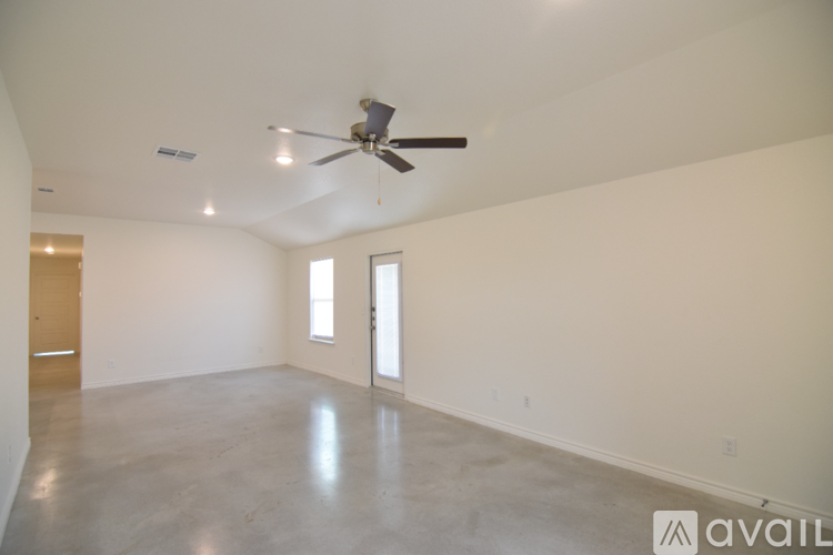 A spacious room with a ceiling fan and two windows.