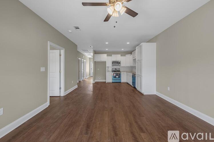 A spacious room with wooden floors and a ceiling fan.