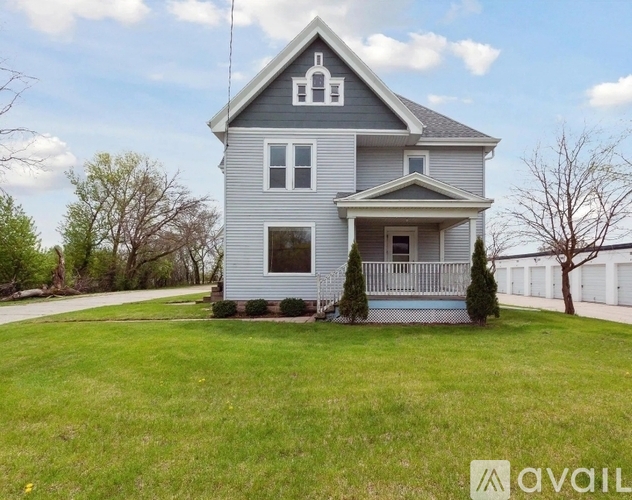A house with a grey exterior and a white fence is for sale.