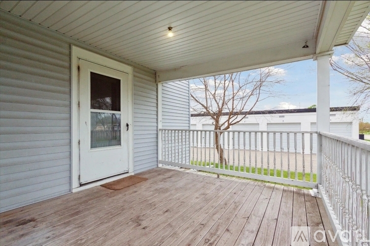 A wooden deck with a white door and a white fence.
