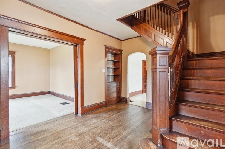 A wooden staircase with a landing and a doorway leading to another room.