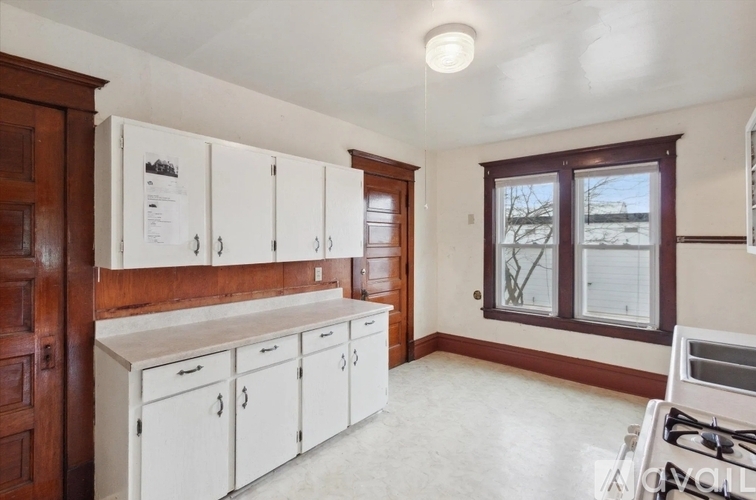 A kitchen with white cabinets and a window.
