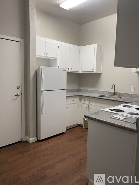 A kitchen with a white refrigerator and cabinets.