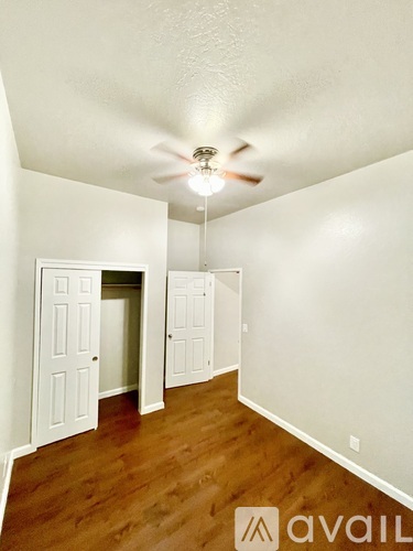 A room with a ceiling fan and wooden floors.
