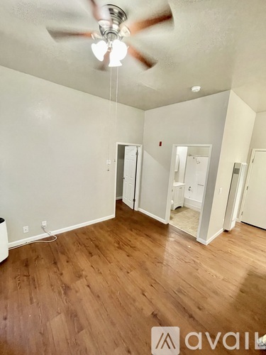 A room with a ceiling fan and wooden flooring.