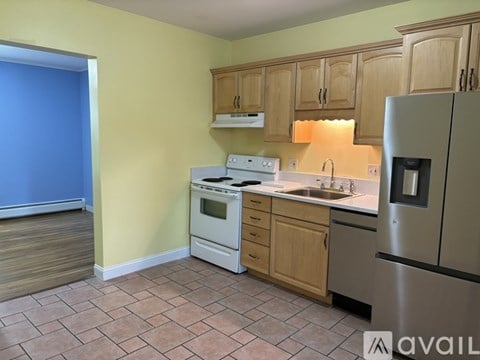 A kitchen with a stove, sink, and refrigerator.