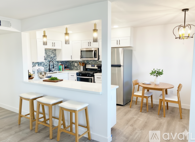 A kitchen with a table and chairs in the foreground and a refrigerator in the background.