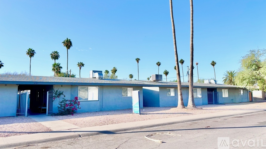 A row of houses with blue trim and white walls are surrounded by palm trees.