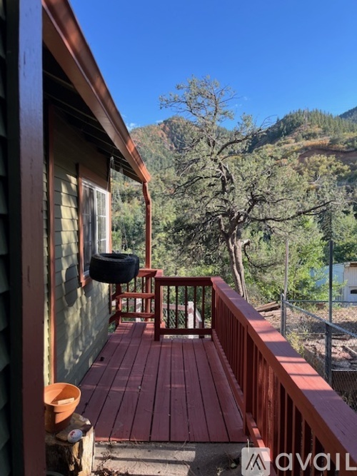 A wooden deck with a red railing and a black tire on it.