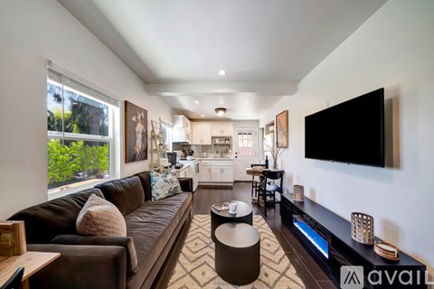 A living room with a brown couch and a flat screen TV mounted on the wall.