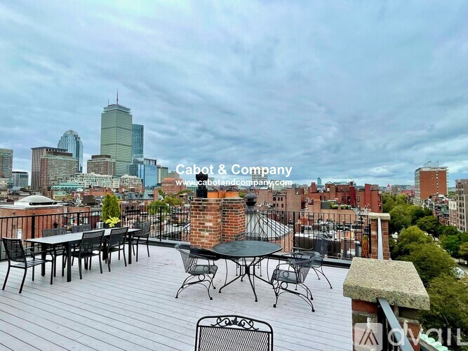 A rooftop patio with a table and chairs overlooking a city skyline.