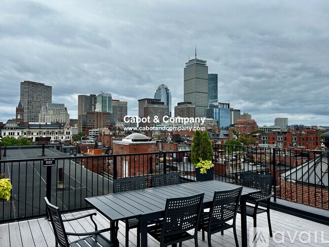 A balcony with a table and chairs overlooking a city skyline.