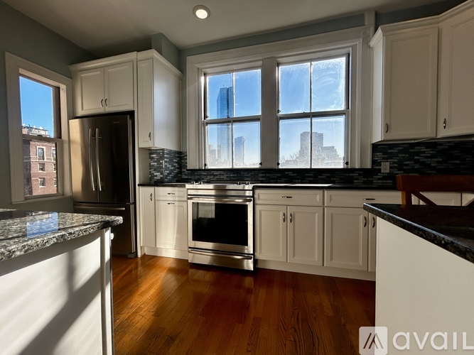 A kitchen with white cabinets and a black countertop.