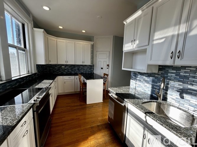 A kitchen with white cabinets and a black countertop.