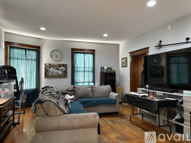 A living room with a couch, a television, and a piano.