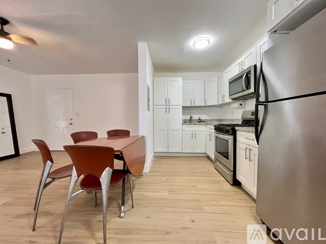 A kitchen with a table and chairs in the foreground and a refrigerator in the background.