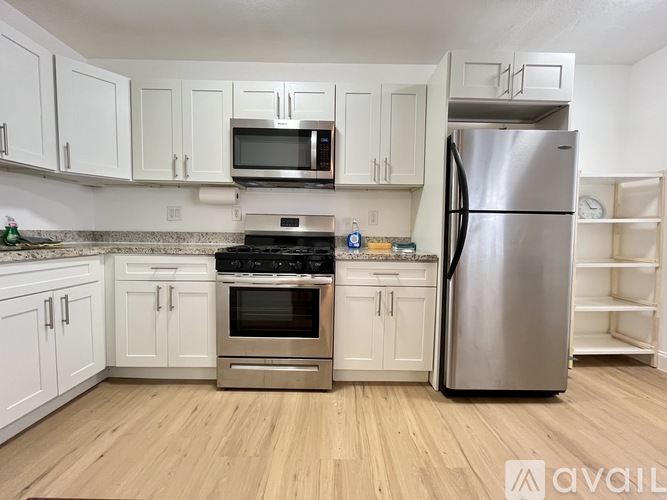 A kitchen with white cabinets and a stainless steel refrigerator.