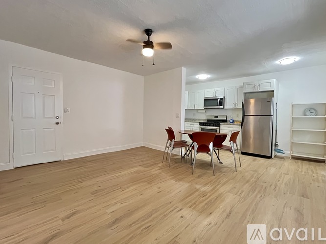A kitchen with a refrigerator, stove, and chairs.