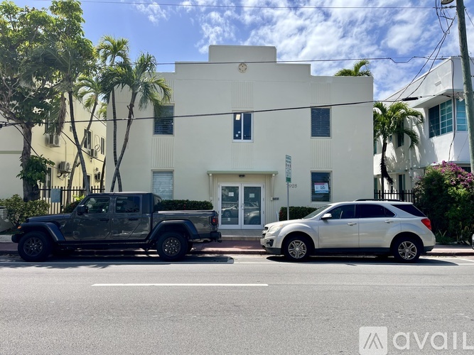 A white building with a black truck and silver car parked in front.