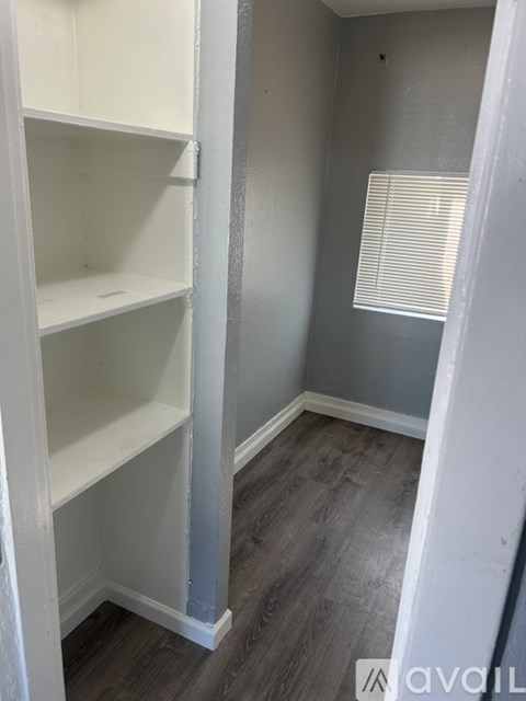 A white shelving unit in a room with grey walls and wooden flooring.