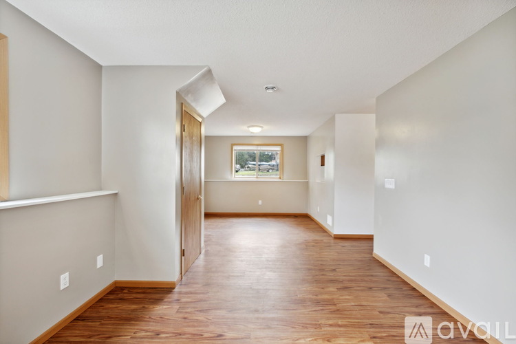 A long hallway with wood floors and white walls.