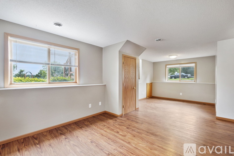 A room with wooden floors and a large window with a view of trees.