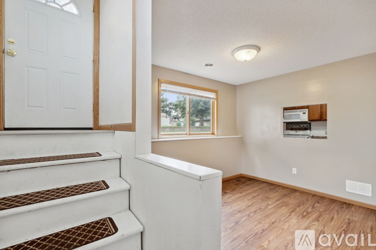 A white staircase with a brown runner leads to a room with a window and a wall-mounted TV.