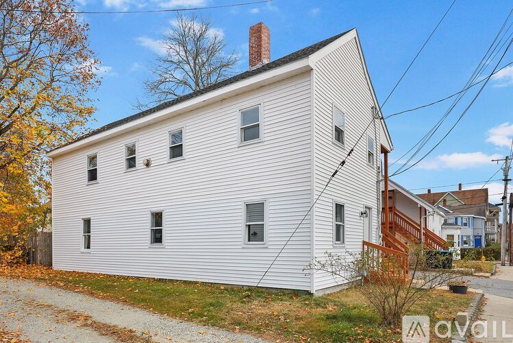 A white house with a brown roof and a sign that says "available" in front of it.