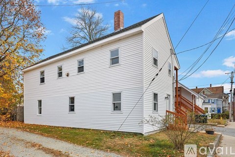 A white house with a brown roof and a sign that says "available" in front of it.