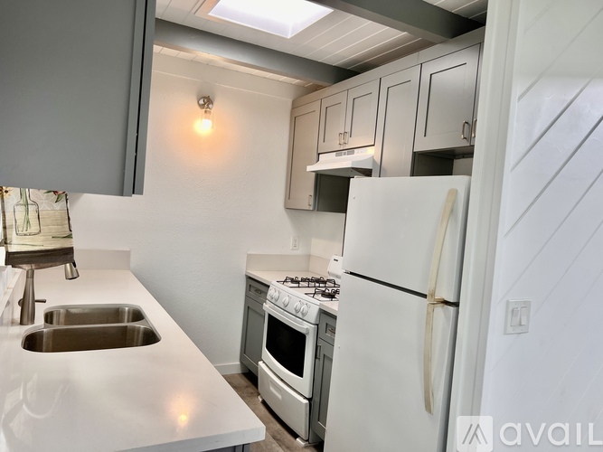 A kitchen with a white refrigerator, sink, and stove.