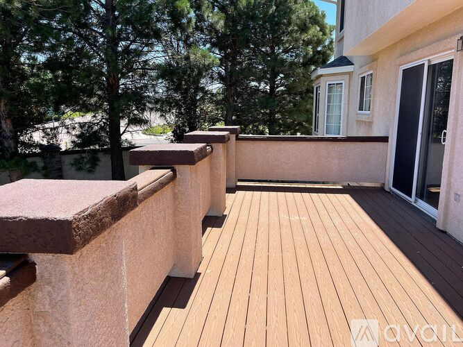 A wooden deck with a railing and trees in the background.