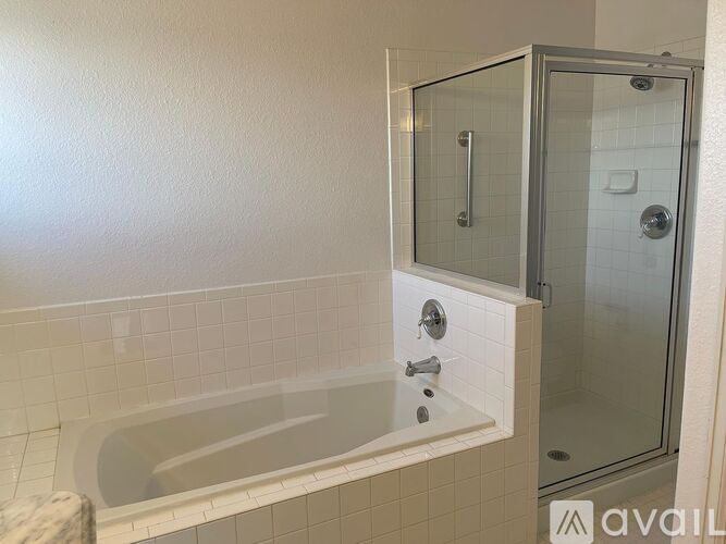 A bathroom with a white tub and a glass shower stall.