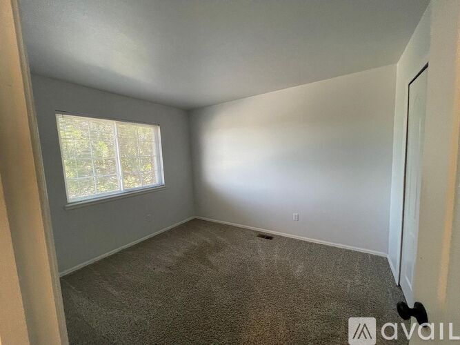 A room with a carpeted floor and a window with blinds.