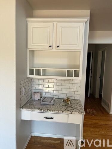A kitchen with white cabinets and a marble countertop.