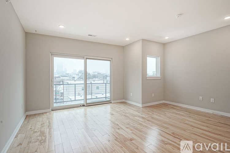 A spacious room with wooden flooring and a large window overlooking a cityscape.