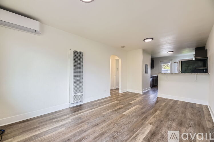 A spacious room with wooden flooring and a wall-mounted television.