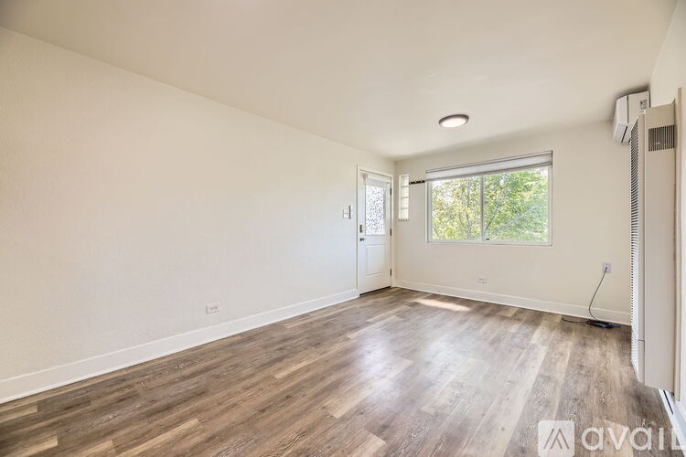 A room with wooden flooring and a window letting in natural light.