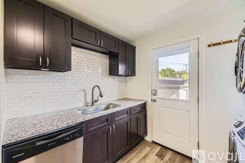 A kitchen with dark brown cabinets and a white tiled backsplash.