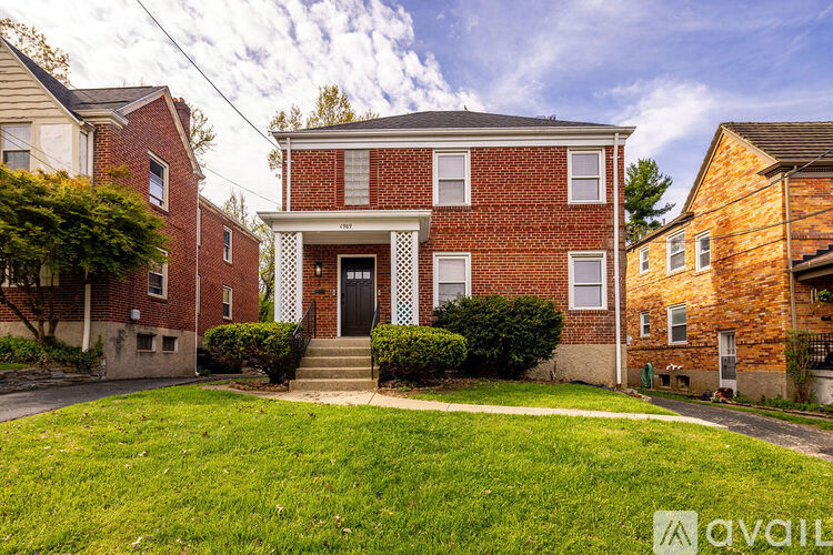 A red brick house with a black door and a white lattice window.