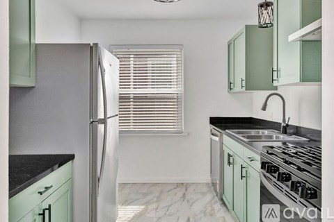 A kitchen with green cabinets and a black countertop.