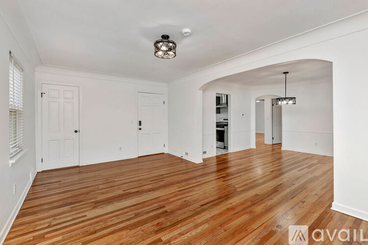 A spacious room with wooden flooring and white walls.