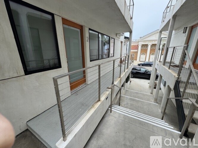 A balcony with a metal railing and a car parked in the background.