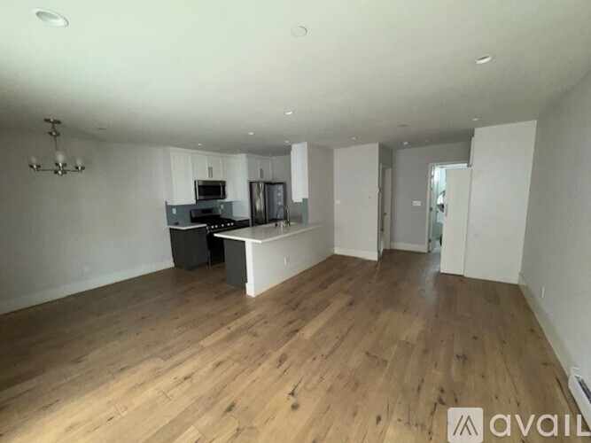 A spacious room with wooden floors and a kitchen area.