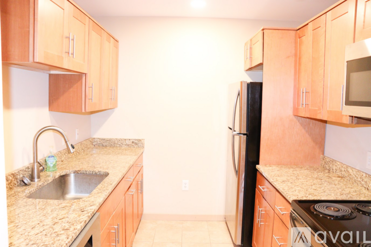 A kitchen with wooden cabinets and a black refrigerator.