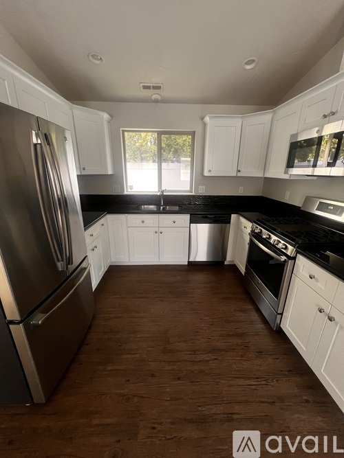 A kitchen with white cabinets and a wooden floor.
