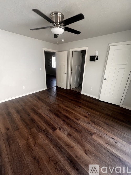 A room with a ceiling fan and wooden flooring.