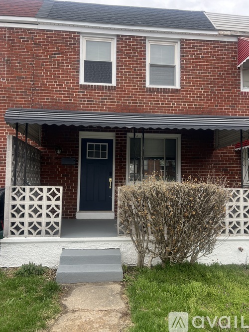A red brick house with a white door and a small bush in front.