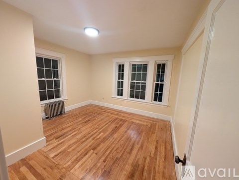 A room with wooden flooring and a window with a white frame.