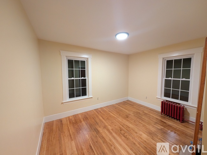 A room with wooden floors and two windows.